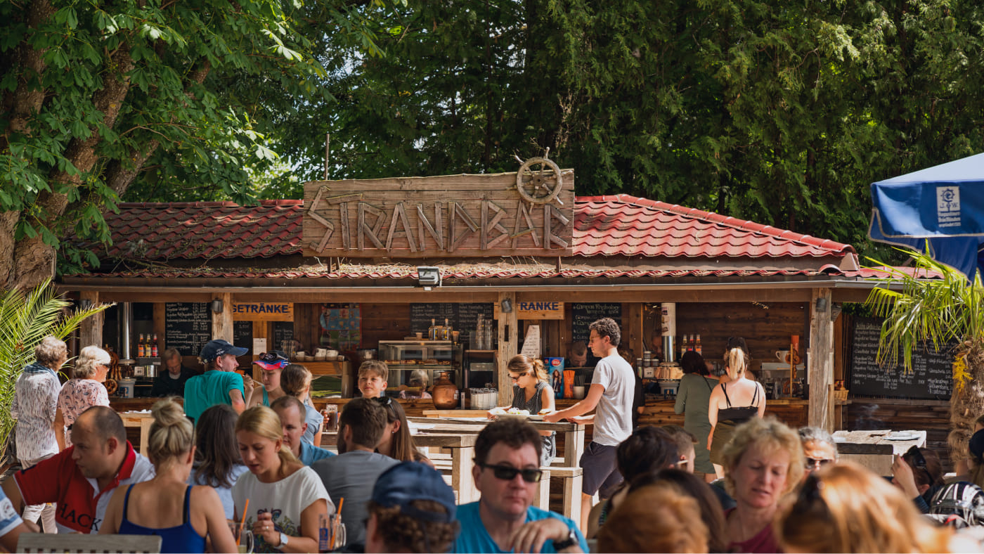 Besucher der Fischer Strandbar mit der Strandbar im Hintergrund