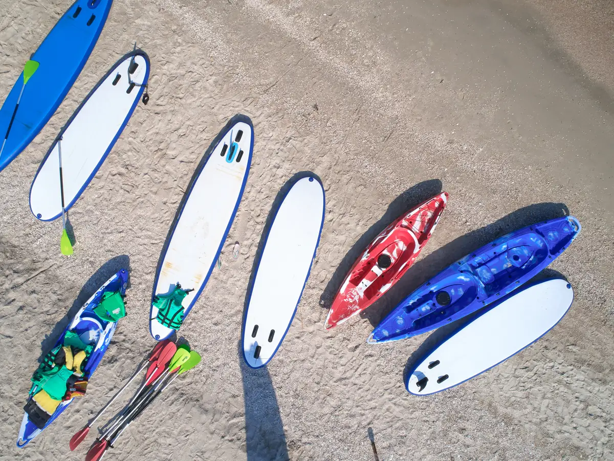 UP-Boards, Paddel und Kajaks liegen am Strand bereit zum Verleih